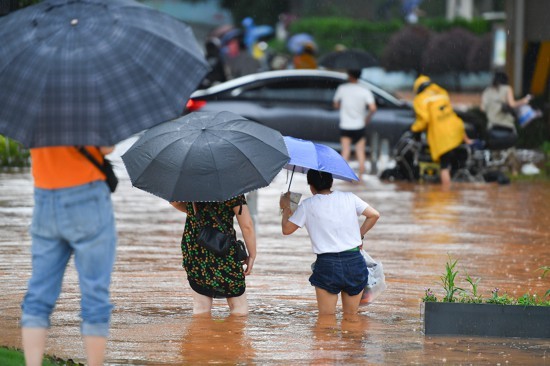 6月24日，在长沙市雨花区万家丽中路附近，市民涉水通行。当日，受强降雨影响，湖南省长沙市部分地段出现内涝。目前，长沙市已经启动防汛三级应急响应。新华社记者 陈泽国 摄