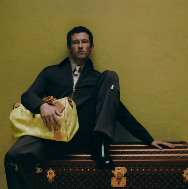 a person sitting on vintage luggage holding a bright yellow designer bag