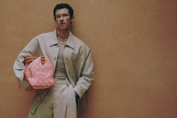 a person holding a pink designer handbag against a textured brown backdrop