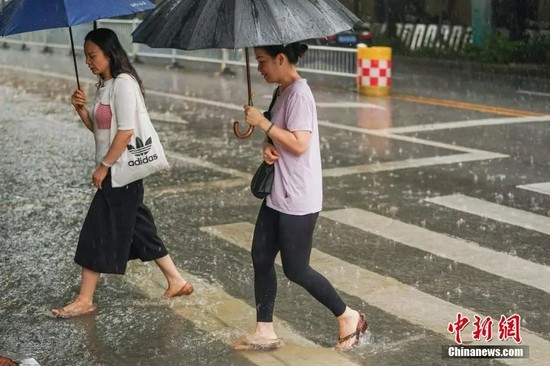 7月22日，受台风“查帕卡”影响，广西南宁市迎来暴雨天气，市民冒雨出行。陈冠言 摄