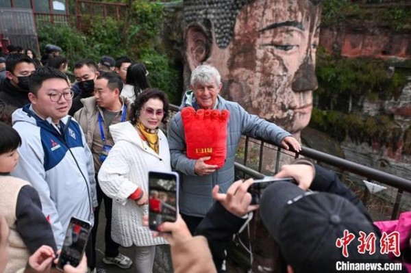 3月15日，四川乐山，大佛佛头观景平台游客与中国国家男子足球队原主教练米卢蒂诺维奇(右一)合影留念。中新社记者 刘忠俊 摄