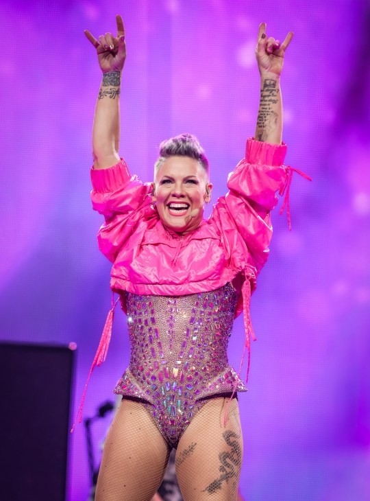 Pink raises her hands in the air as she performs during her Trust Fall tour in a pink embellished leotard and cropped neon anorak at Kaseya Center on November 14, 2023 in Miami, Florida