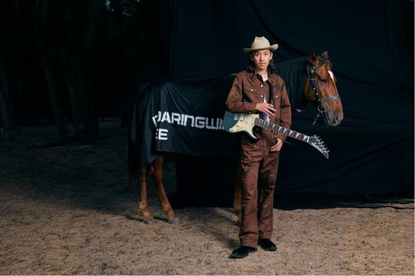 a man holding a guitar next to a horse