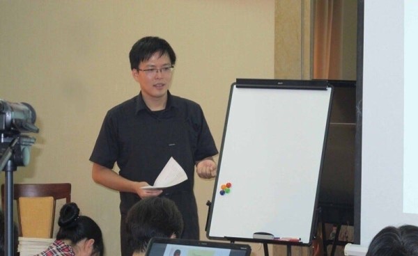 a person is presenting in front of an audience using a whiteboard