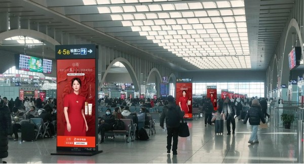a busy train station interior with advertisements and travelers