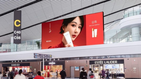 an advertisement in an airport featuring skincare products against a red background