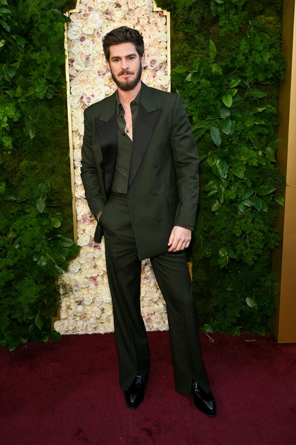 man in a formal green suit standing in front of a floral backdrop