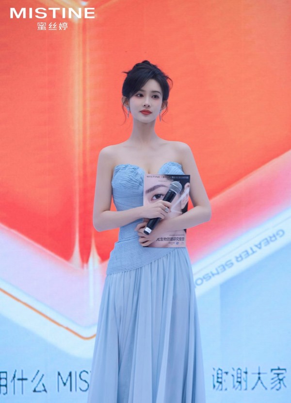 a presenter holding a magazine and a microphone at a promotional event