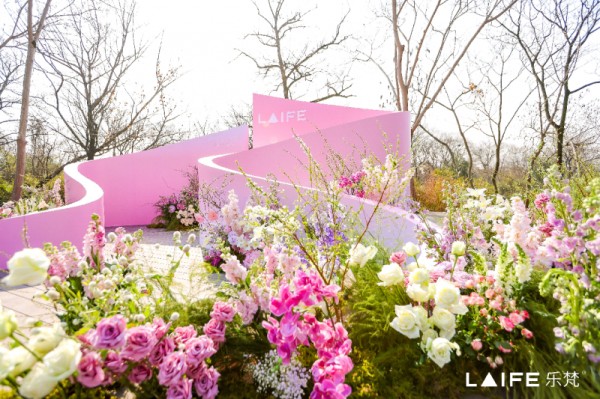 floral arrangement with pink and white flowers surrounding a pink curved installation with the text laife