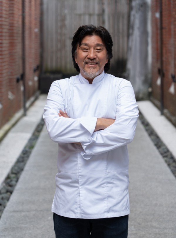 chef standing confidently in a narrow pathway between brick walls