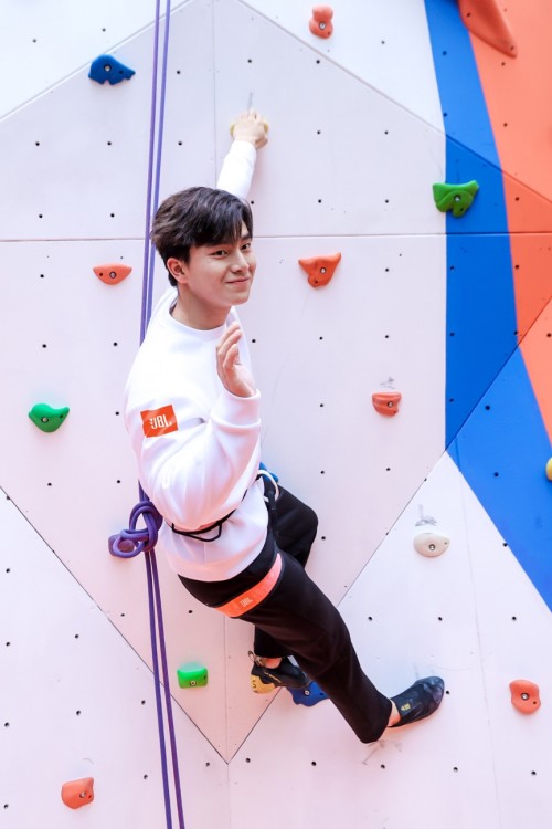 individual climbing a rock wall utilizing climbing holds