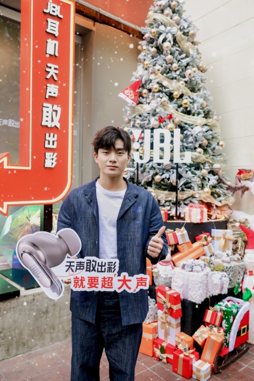 promotional display featuring a person near a christmas tree and a jbl speaker advertisement