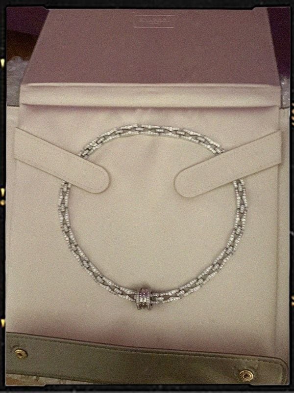 jewelry display featuring a circular necklace with decorative elements contained within a soft pouch