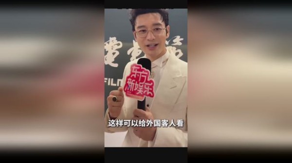 黄晓明主持人手持带有“新娱乐”字样的麦克风，展示给外国观众观看