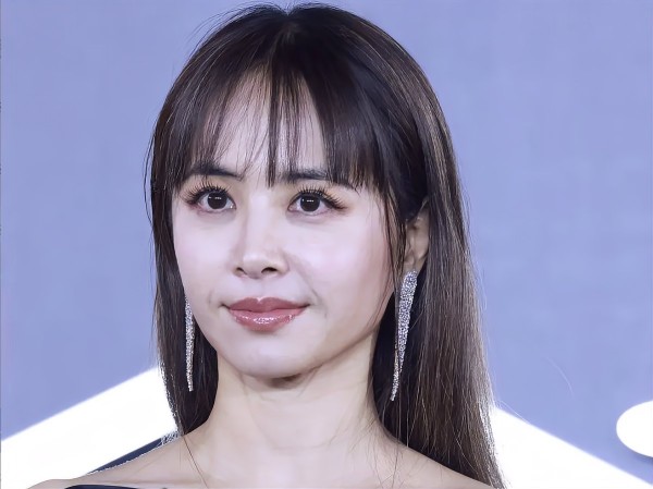 蔡依林一位女性佩戴闪亮耳环，微笑着面对镜头。