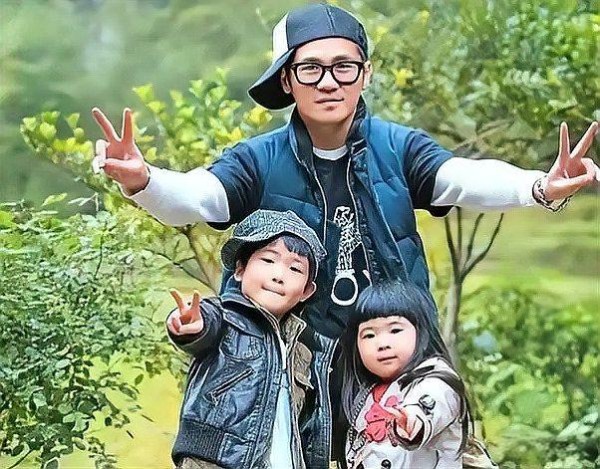曹格曹华恩曹三丰一家三口在户外绿意环境中快乐合影，三人都比出“V”手势。