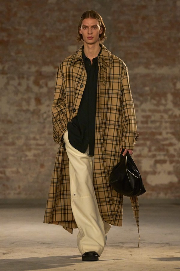 model showcasing a fashion outfit with a long plaid coat and a black bag