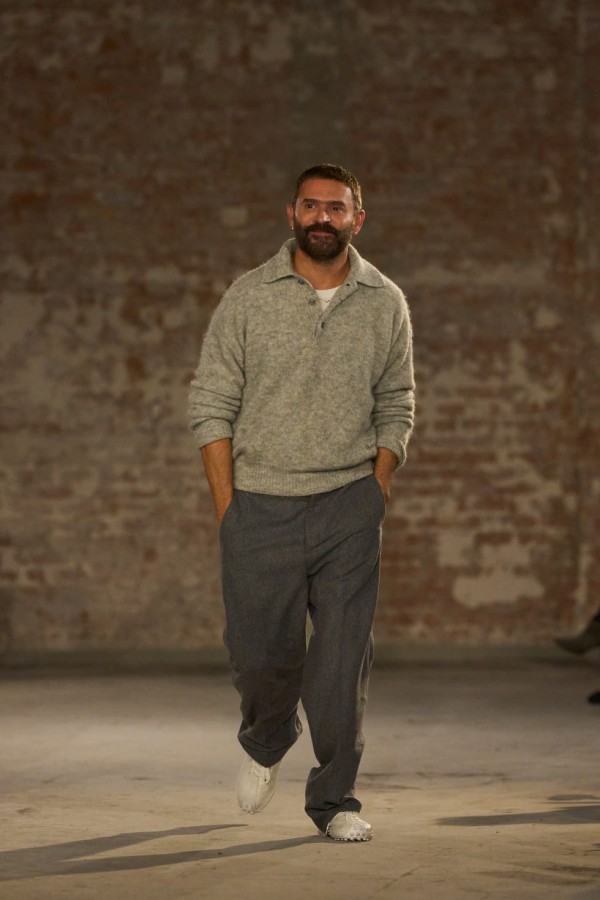 a model walking on a runway showcasing a casual outfit under studio lighting