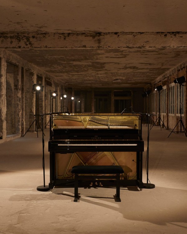 piano positioned in an empty industrial space with lighting equipment
