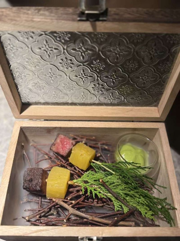 屈雨瑜研发的湘西烟熏牛小排配椒麻慕斯。盒子是定制的，屈雨瑜将老西关的窗花元素放在了盒盖上。新京报记者 吴淋姝 摄