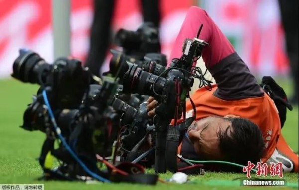 一名摄影师为了调整了他的远程摄像机,直接侧卧在地。