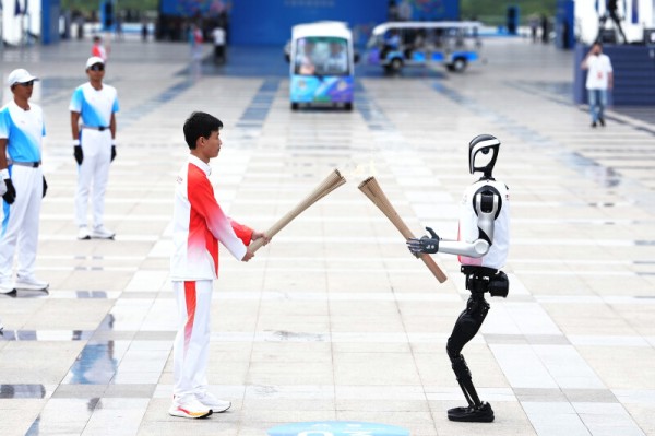 11月2日，火炬手人形机器人“夸父”与王裕宁（左）在火炬传递中。图源 新华社