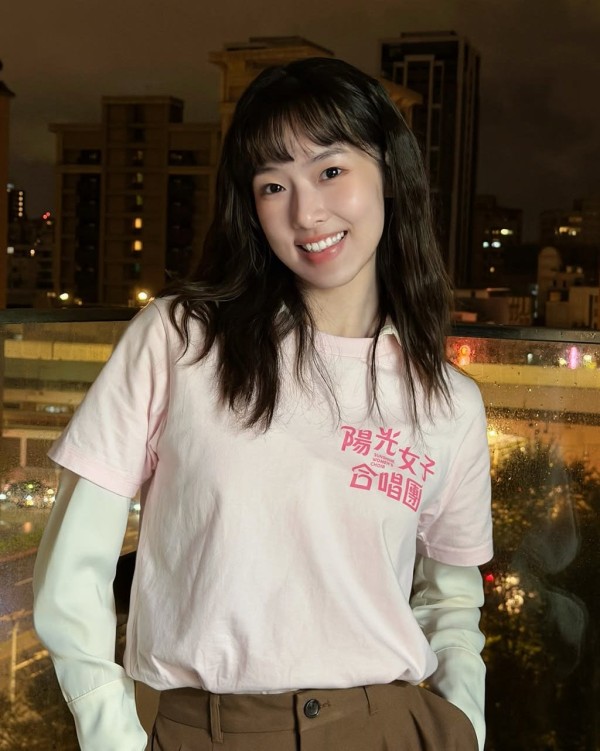 individual posing in urban night scene wearing a pink tshirt and beige trousers