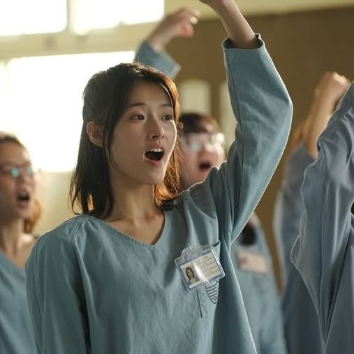 group of individuals wearing blue uniforms raising their hands