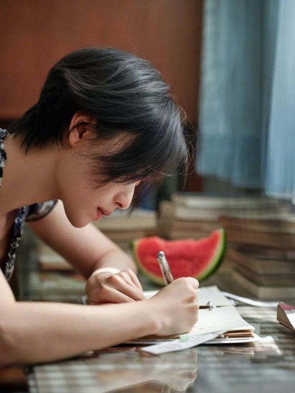 倪妮低头写字,格纹裙尽显文艺感。