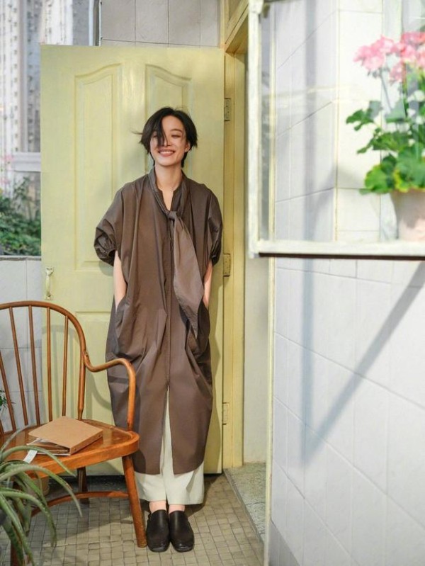 倪妮立门前,咖色裙笑眼明媚。