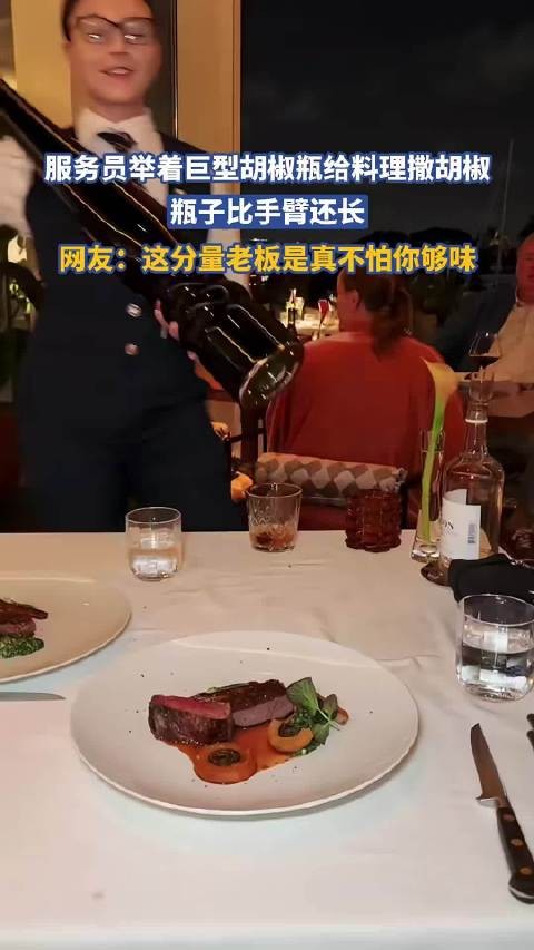 服务员举着巨型胡椒瓶给牛排撒胡椒,瓶子比手臂还长