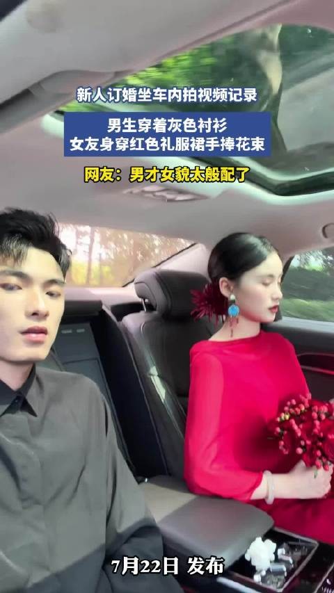 新人订婚坐车内拍视频记录，男生穿着灰色衬衫，女友身穿红色礼服裙手捧花束！