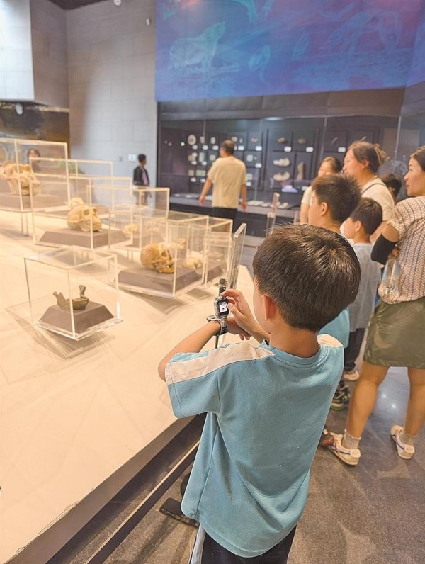 北京房山周口店北京人遗址博物馆内，儿童在使用电话手表拍照。本报记者 张云摄/光明图片