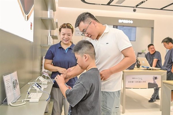 江西宜春市袁州区，家长带着孩子挑选电话手表。周亮摄/光明图片